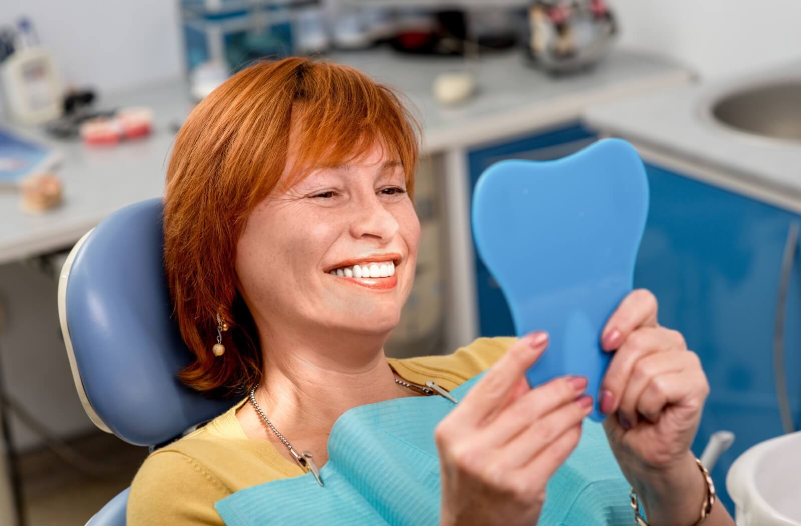 Senior smiling and looking in the mirror, happy with the results of their new dental implants in Mississauga.