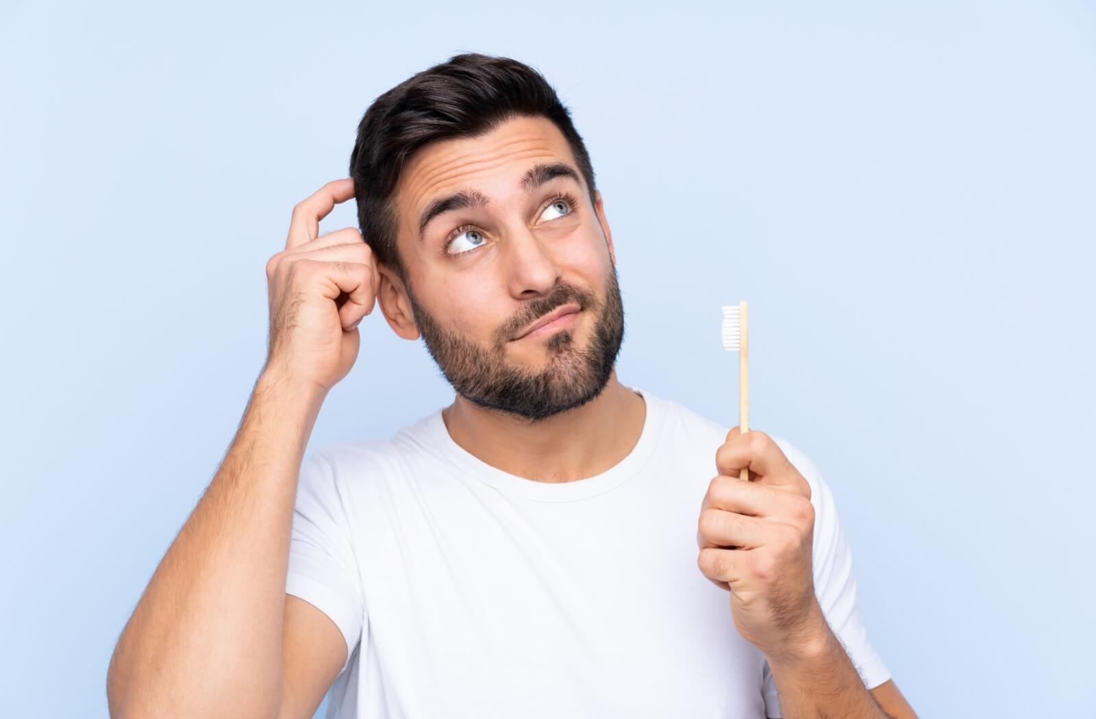 A person holding a toothbrush, wondering whether they might need a root canal.